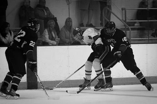 Sophomore Sam Komrower battles for the puck against a defender next to the boards. [Photo Courtesy of Facebook ]